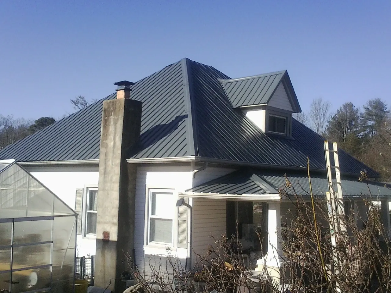 Dark blue standing seam metal roof on a white farmhouse with dormer — Slate & Tile Roof Repair by Roofing Brothers in Fairchance