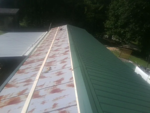 Old rusted panels beside newly installed green metal roofing — Wind Damage Roof Repair by Roofing Brothers in Fairchance