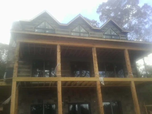 Dormers and porch framing on a large log home under construction — Roof Coating work by our crew in Fairchance