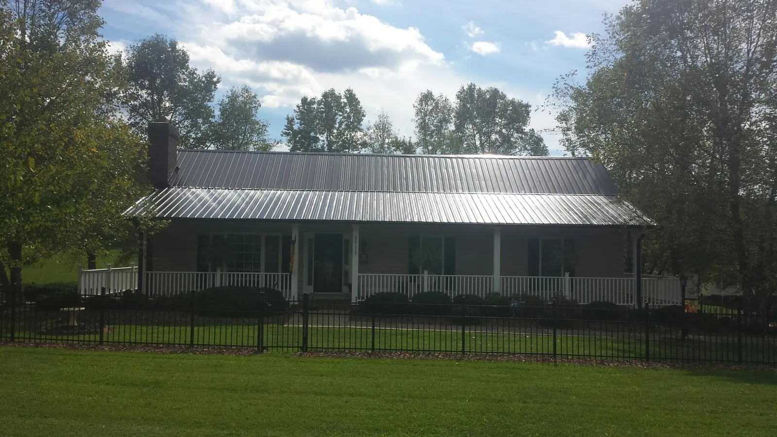 Gray metal roof on a brick ranch with a full width front porch — Gutter Guard Installation work by our crew in Fairchance