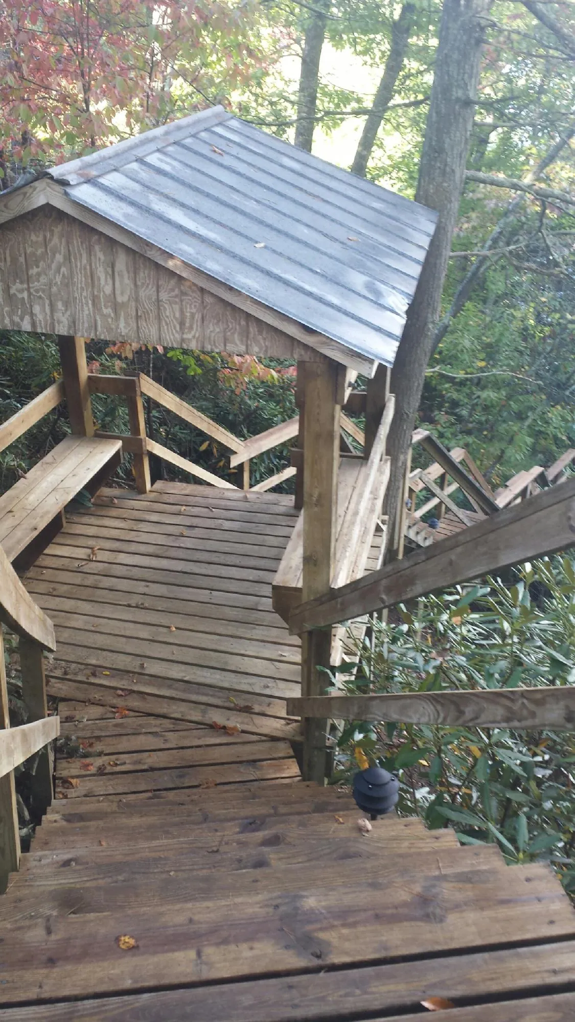 Metal roofed shelter over wooden steps on a wooded walkway — Skylight Repair & Installation work by our crew in Fairchance