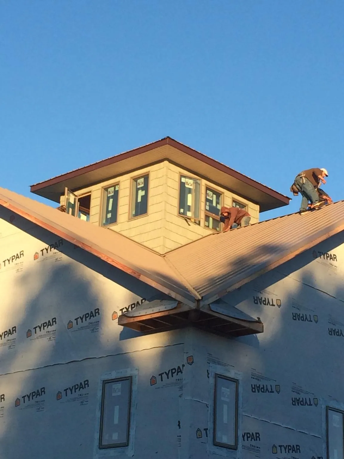 Roofers working around a rooftop cupola on a new metal roof at sunset — Roof Waterproofing in Fairchance by Roofing Brothers